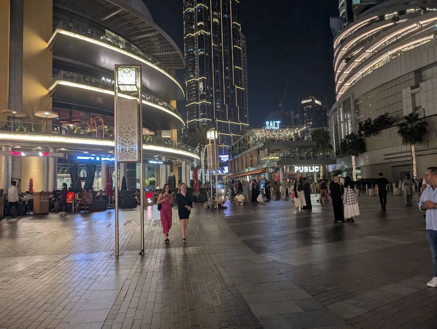People strolling a lit promenade at night in Downtown Dubai