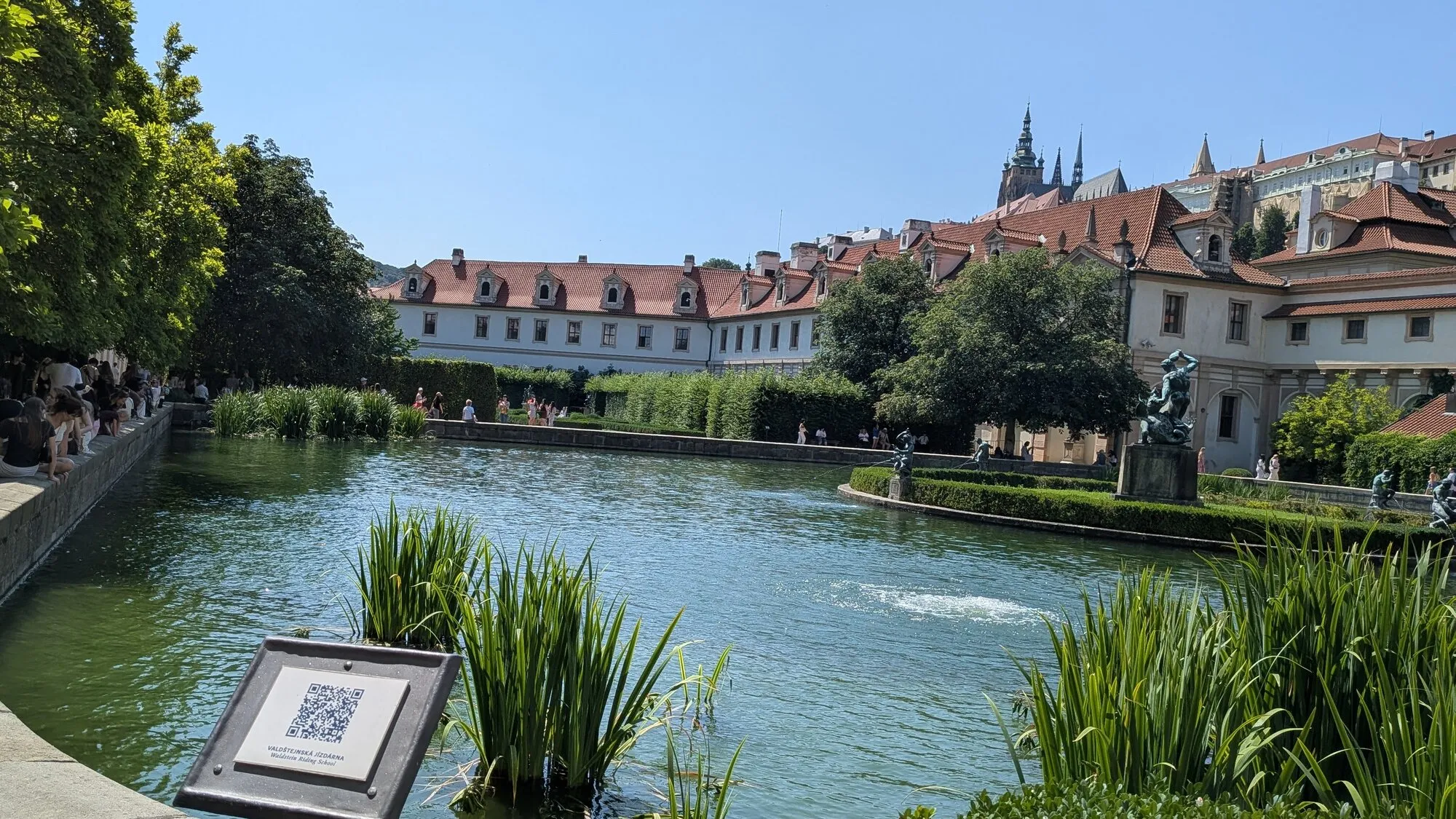 The big pond in the Wallenstein Garden in Prague, with reeds in the water, the Hercules fountain on its island, the long palace wings behind and the spires of St Vitus Cathedral rising above them on the castle hill
