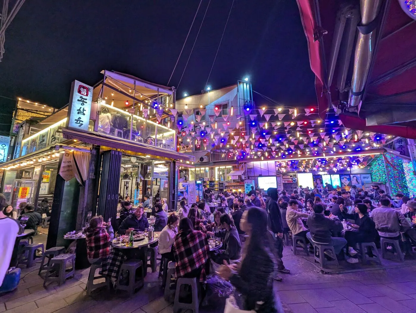 A crowded open-air bar lit purple at night in Ikseon-dong, Seoul