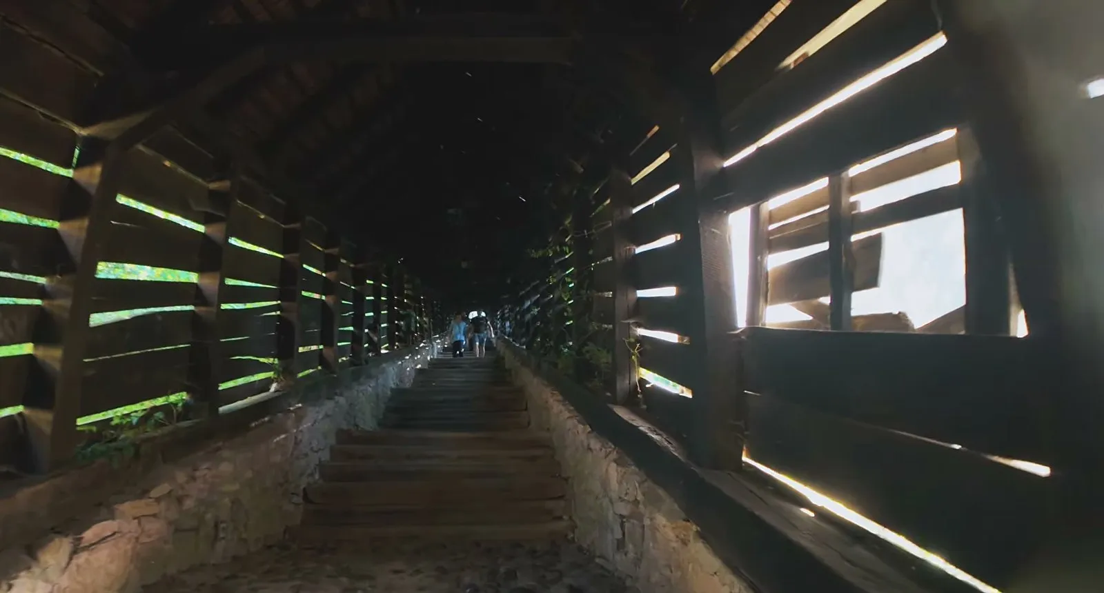 Inside the covered wooden Scholars’ Stairs in Sighișoara, with sunlight coming through the slatted walls onto the steps